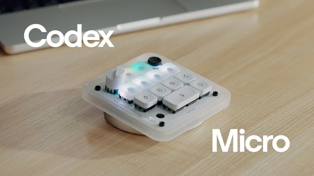 Codex Micro, et lite hvitt kontrollpanel med opplyste taster, en dreieskive og en styrespak, på et trebord foran en bærbar datamaskin.